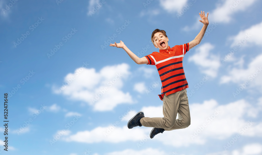 freedom, motion and happiness concept - happy smiling young boy jumping in air over blue sky and clouds background freedom, motion and happiness concept - happy smiling young boy jumping in air over blue sky and clouds background