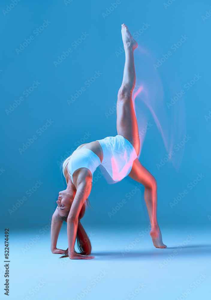 Full body side view of slim female in activewear standing in gymnastic handstand in the splits. Motion blur effect.