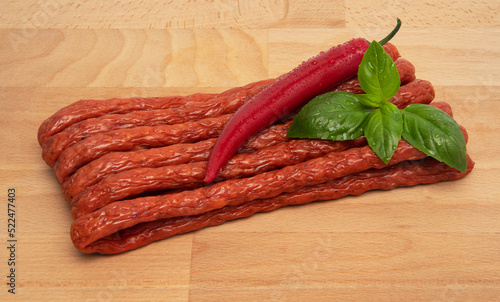 Thin Dry Smoked Pork or beef meat Polish Kabanos sausages Isolated on a wooden board