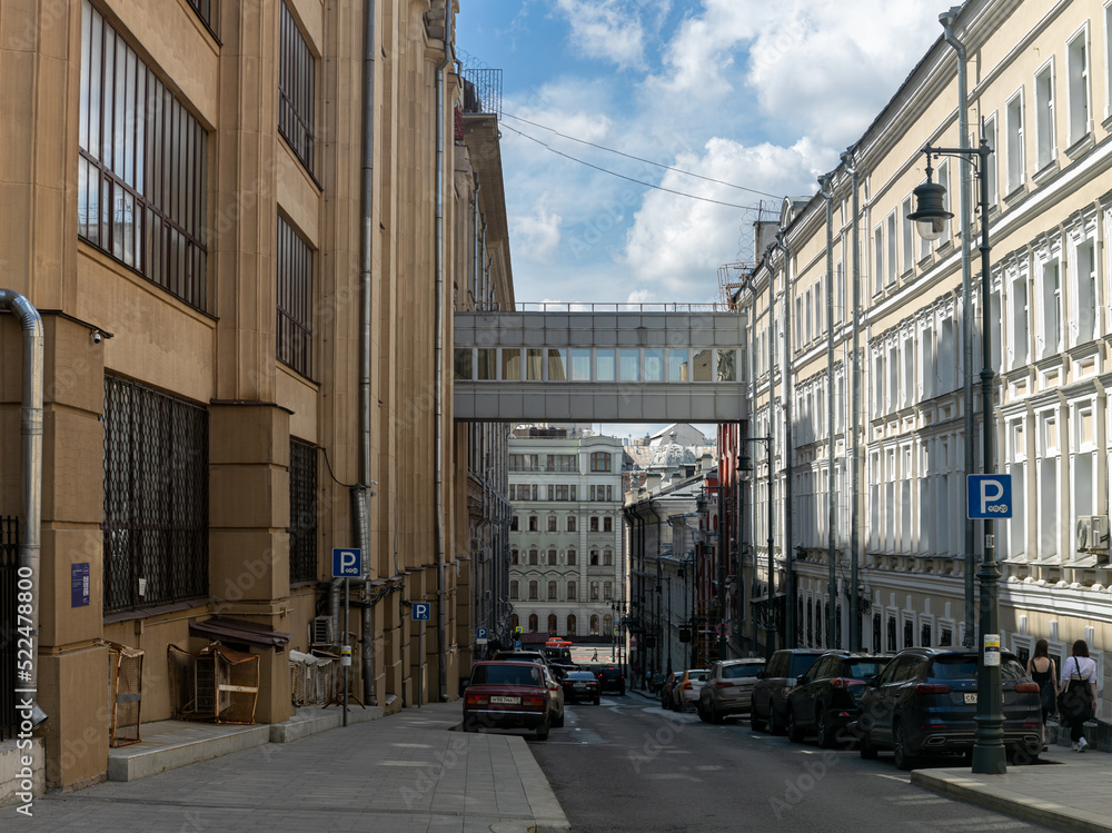 Glued panorama of the city in high resolution: Moscow, a wide lane, drains on the walls of houses. Cars are parked along the street. Random passers-by walk along the sidewalk