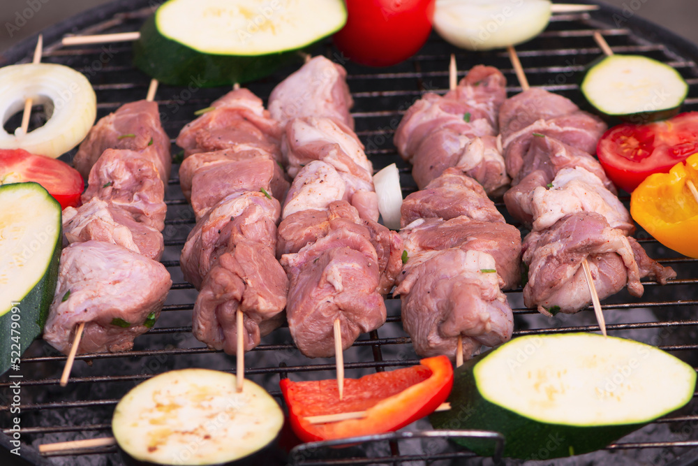 raw pork neck meat is cooked on the grill with vegetables in nature in summer
