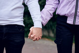 Young couple in love holding hands in the park. Close up picture of girlfriend and boyfriend, standing walking in the street. Romantic relationship in teenage time.