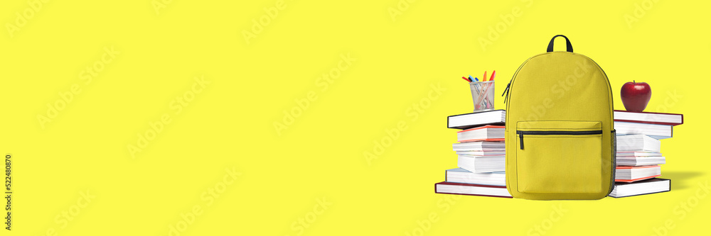 Back to school. Yellow backpack with books and school stuff on blue background Back to school. Yellow backpack with books and school stuff on blue background