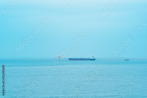 foggy seascape with a tanker near an oil terminal located far out to sea © Evgeny