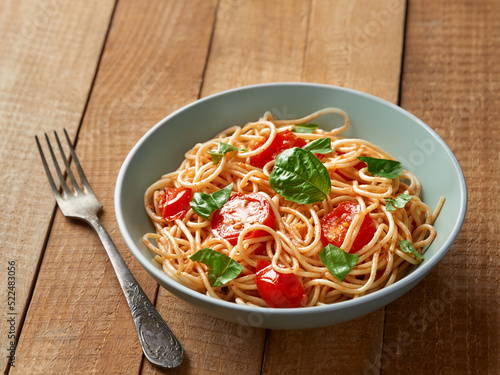Spaghetti with cherry tomatoes and basil close-up on wooden background from a high angle view indoors