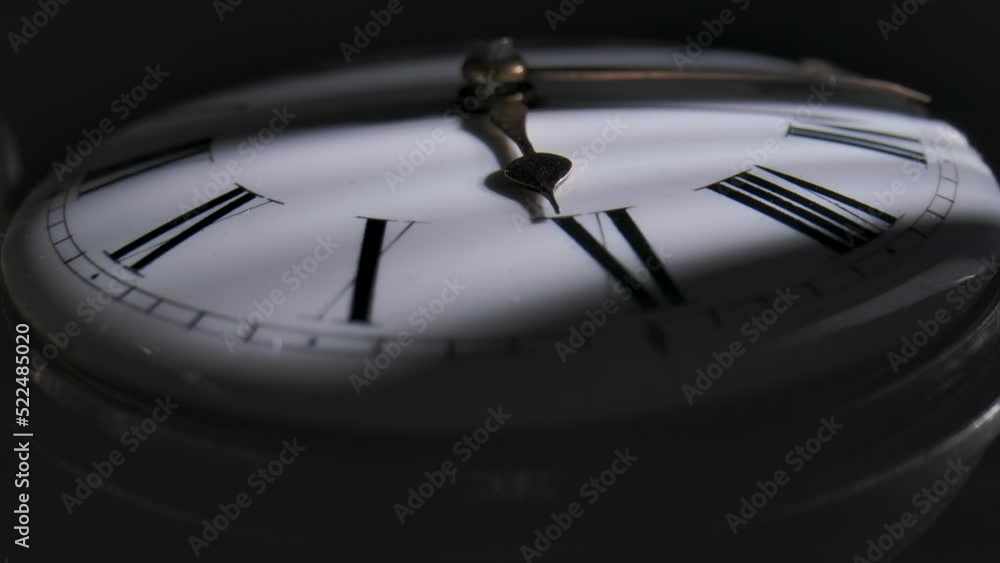 Antique pocket watch with a shadow on the dial and rotating hands in time lapse video. Old silver pocket watch with round dial and ticking hands. Running clock hands in circle in time lapse. Close up.