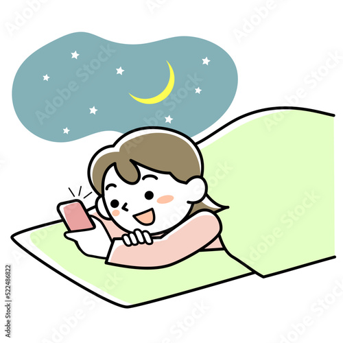 布団の中でスマホを見て夜更かしする若い女性