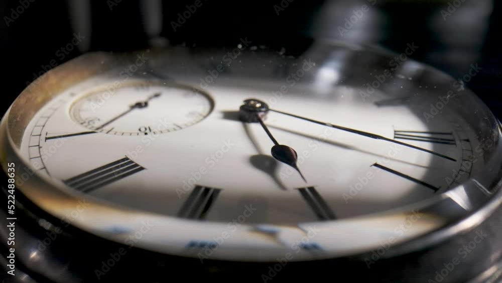 Antique pocket watch with a shadow on the dial and rotating hands in time lapse video. Old silver pocket watch with round dial and ticking hands. Running clock hands in circle in time lapse. Close up.