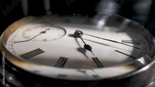 Antique pocket watch with a shadow on the dial and rotating hands in time lapse video. Old silver pocket watch with round dial and ticking hands. Running clock hands in circle in time lapse. Close up.