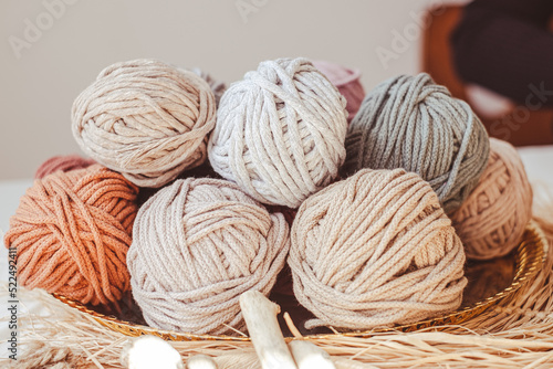 Basket with cozy cotton twine balls. Homely atmosphere. Hobby knitting. Cotton twines in warm colors. Blurred background.