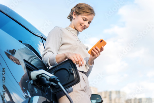 Young woman with an electric car at charging station in Chisinau, Moldova