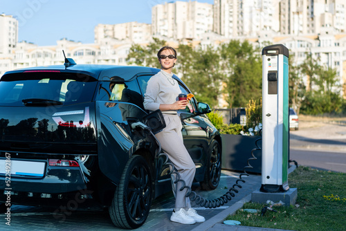 Young woman with an electric car at charging station in Chisinau, Moldova