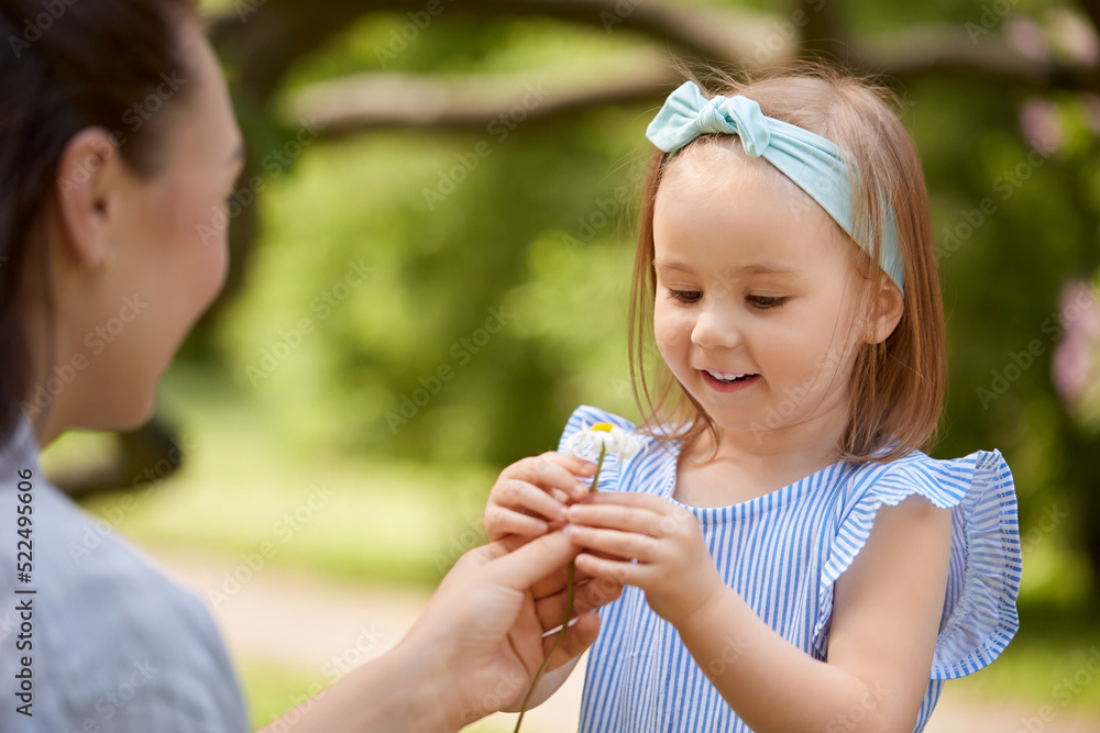 family, motherhood and people concept - happy mother and little daughter with chamomile flower at summer park or garden family, motherhood and people concept - happy mother and little daughter with chamomile flower at summer park or garden