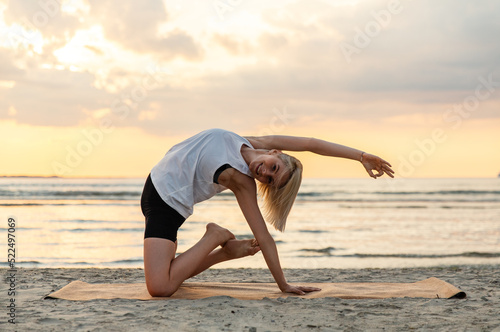 Fotografia fitness, sport, and healthy lifestyle concept - woman doing yoga camel pose on b