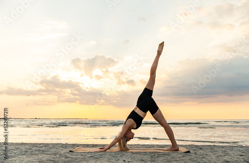 fitness, sport, and healthy lifestyle concept - woman doing yoga downward facing dog pose on beach over sunset
