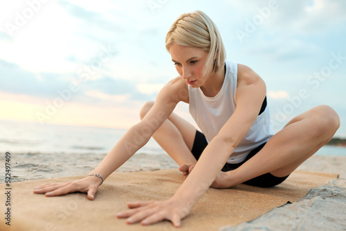 fitness, sport, and healthy lifestyle concept - woman doing yoga stretching pose on beach over sunset © Syda Productions