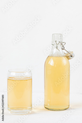 Homemade kombucha fermented drink in glass and bottle on white background. Heathy probiotic beverage with bubbles. Summer non alcoholic drinks. Copy space