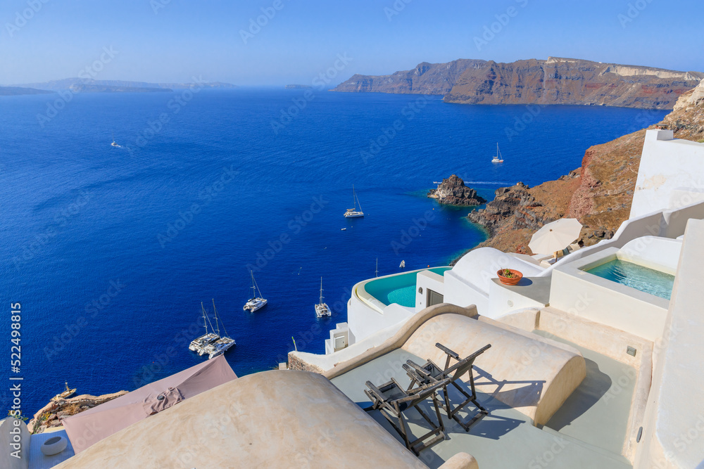 View of Santorini Island in Greece: two deck chairs with pool on the roof of a typical house of Oia.