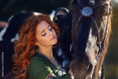 Φωτογραφία Medieval woman princess in green dress sits astride black steed horse