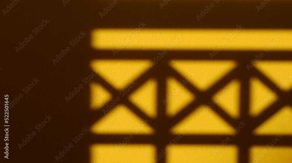 shadow of fence on yellow concrete wall texture