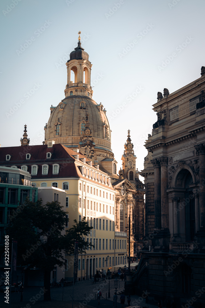 The dome of Frauenkirche peeking up behind other buildings in the evening sunlight in Dresden Germany
