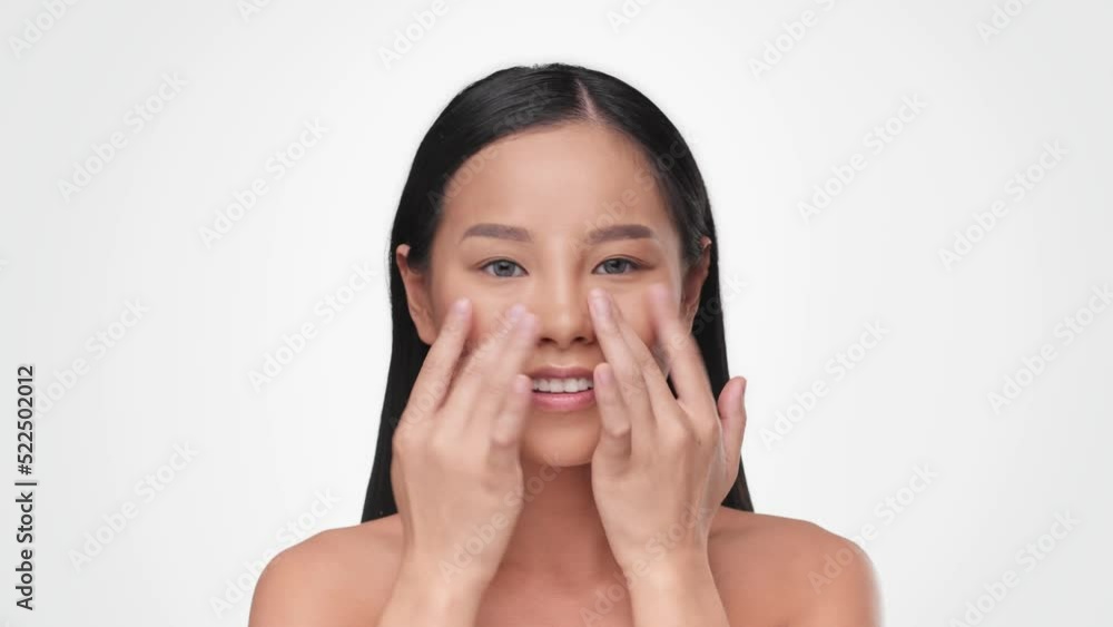 Asian young woman massaging her face. Natural healthy face. Close up portrait Adorable half-naked female. Advertising fresh clean healthy skin care concept. Healthy model on white background in studio Asian young woman massaging her face. Natural healthy face. Close up portrait Adorable half-naked female. Advertising fresh clean healthy skin care concept. Healthy model on white background in studio