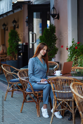 Beautiful confident woman. Woman on the street at the table . Business consultant, to note down, to make notes. Business meeting. Woman with notebook. Business look. © Don_Pomidor