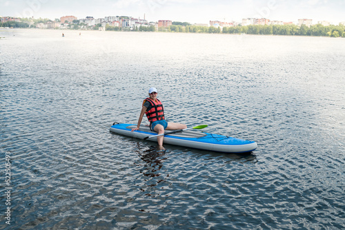 Young Woman wear Life vest rest on Paddle Board after the first training session © RomanR