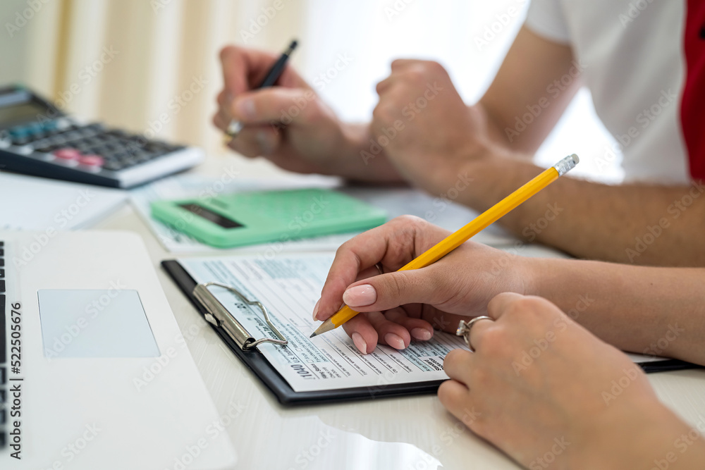 Fototapeta premium Woman filling US tax form with laptop and calculator at office