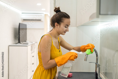 woman in yellow rag cleaning her kitchen sink