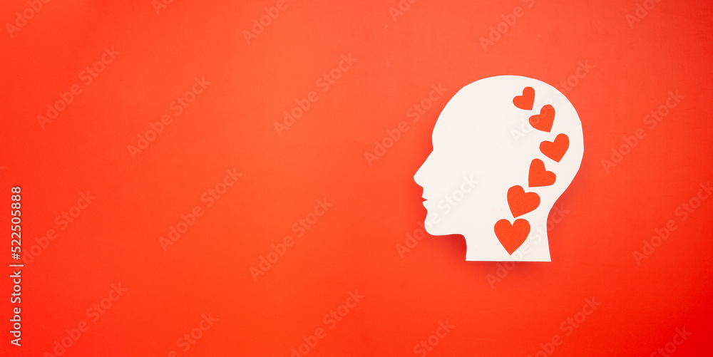 Top view of a white head with a red heart made from paper on a red background Top view of a white head with a red heart made from paper on a red background