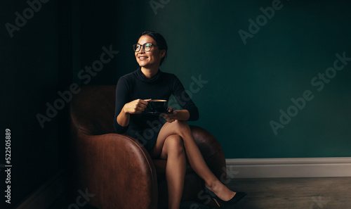 Canvas Print Businesswoman sitting on armchair with cup of tea