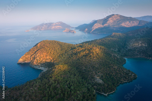 Obraz na płótnie Aerial view of morning seascape and moutain islands. The sun rises gradually over islands. Sun rays illuminate blue lagoon in Mediterranean, Turkey. w salonie