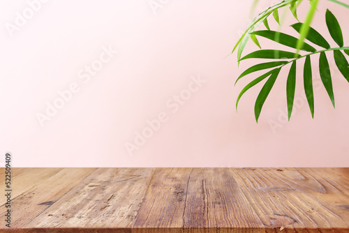 wooden table in front of interior wall and tropical green plant background. for product display and presentation.