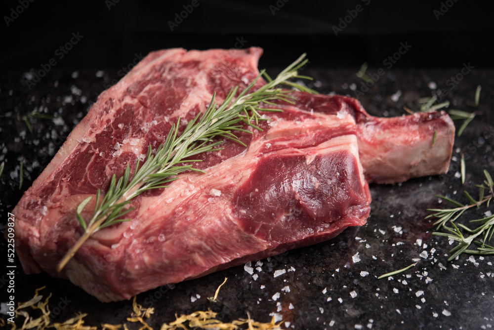 Raw steak with bone served on board