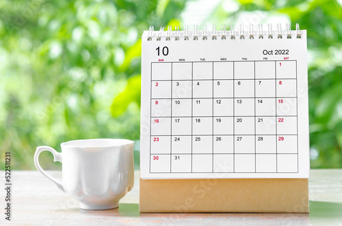 The October 2022 Calendar desk for organizer to plan and reminder on wooden table on nature background.