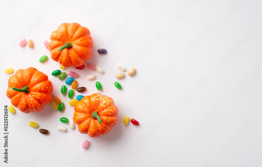 Halloween concept. Top view photo of orange pumpkins and candies on isolated white background with copyspace - obrazy, fototapety, plakaty 
