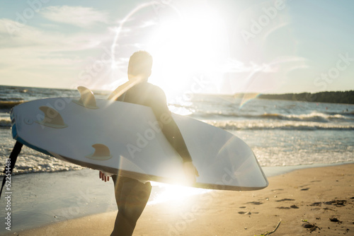 Photography A male surfer goes in for sports at sea uses a surfboard in a wetsuit