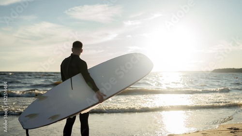 A male surfer goes in for sports at sea uses a surfboard in a wetsuit