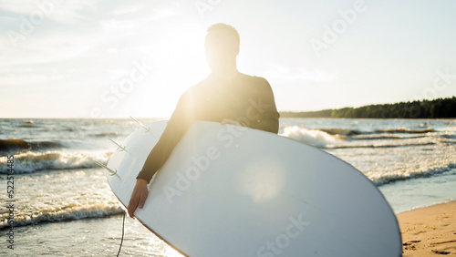 A male surfer goes in for sports at sea uses a surfboard in a wetsuit