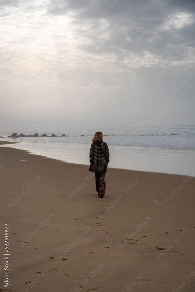 Femme qui marche sur la plage en hiver