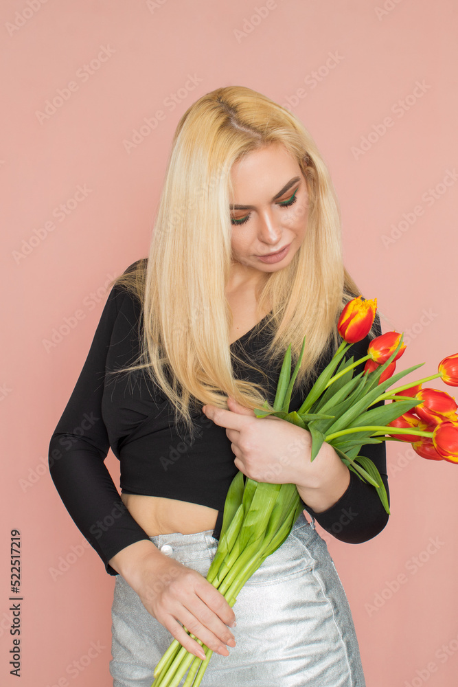 Naklejka premium Fashion blonde woman holding red tulips in her hands