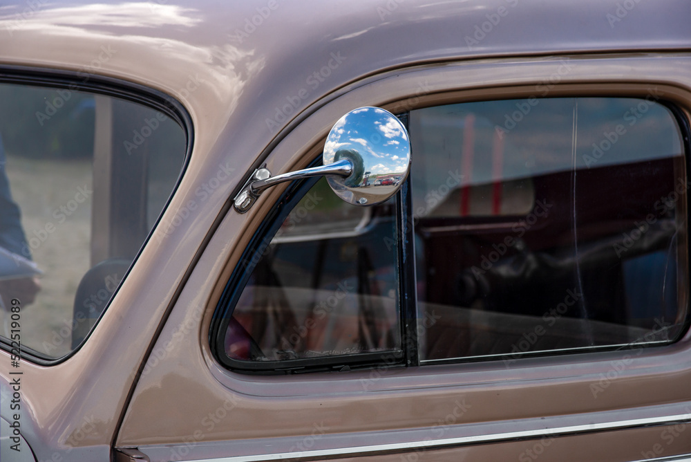 Design detail of vintage classic car with mirror with sky reflection and steering wheel