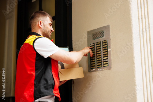 Obraz na płótnie Delivery man pressing button of intercom to enter building w salonie
