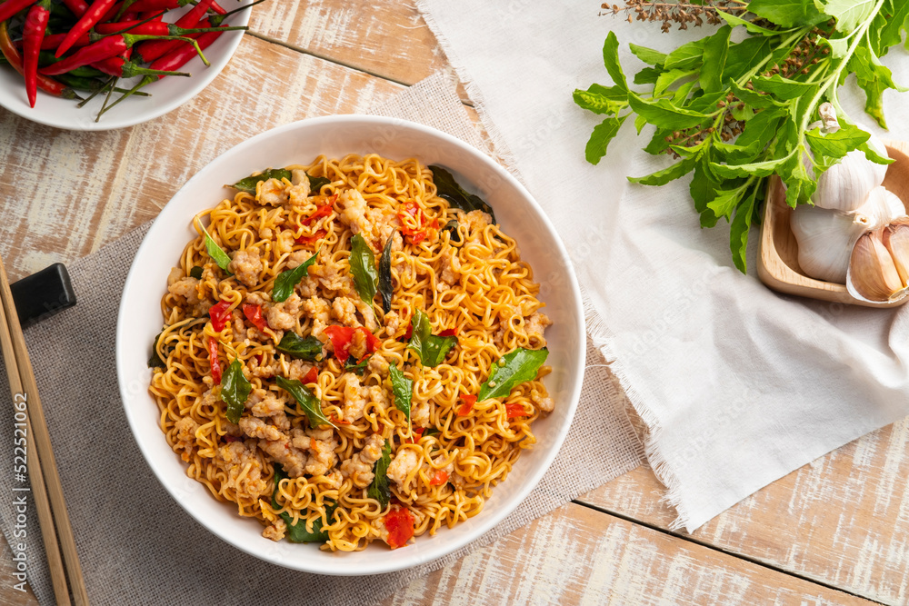 Spicy stir fried instant noodle with minced pork and holy basil leaves in white plate.Top view Spicy stir fried instant noodle with minced pork and holy basil leaves in white plate.Top view