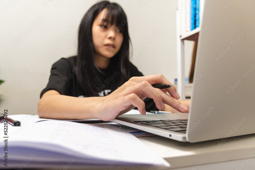 Asian teen girl use computer laptop technology internet online research information social network and education homework on table. Asian teen girl use computer laptop technology internet online research information social network and education homework on table.