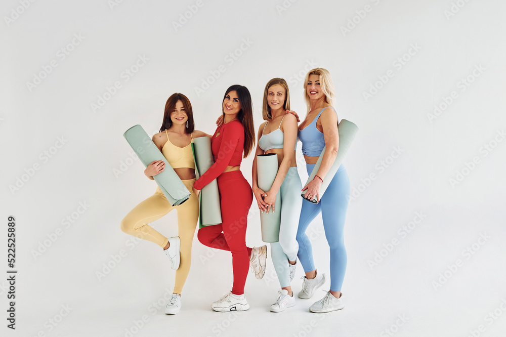 Obraz premium Group of people standing together. Beautiful women in sportive clothes is indoors in the studio