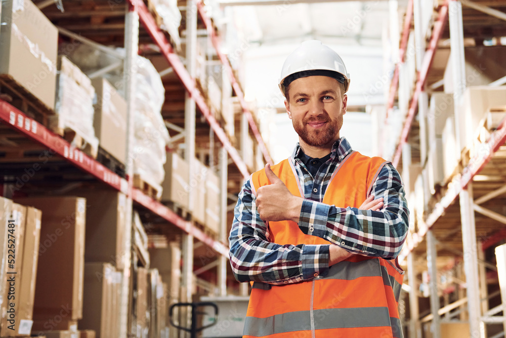 Standing with arms crossed. Employee in uniform is working in the storage at daytime Standing with arms crossed. Employee in uniform is working in the storage at daytime