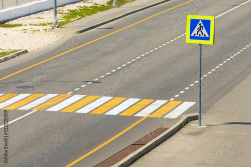 Pedestrian crossing with a road sign through the city highway.