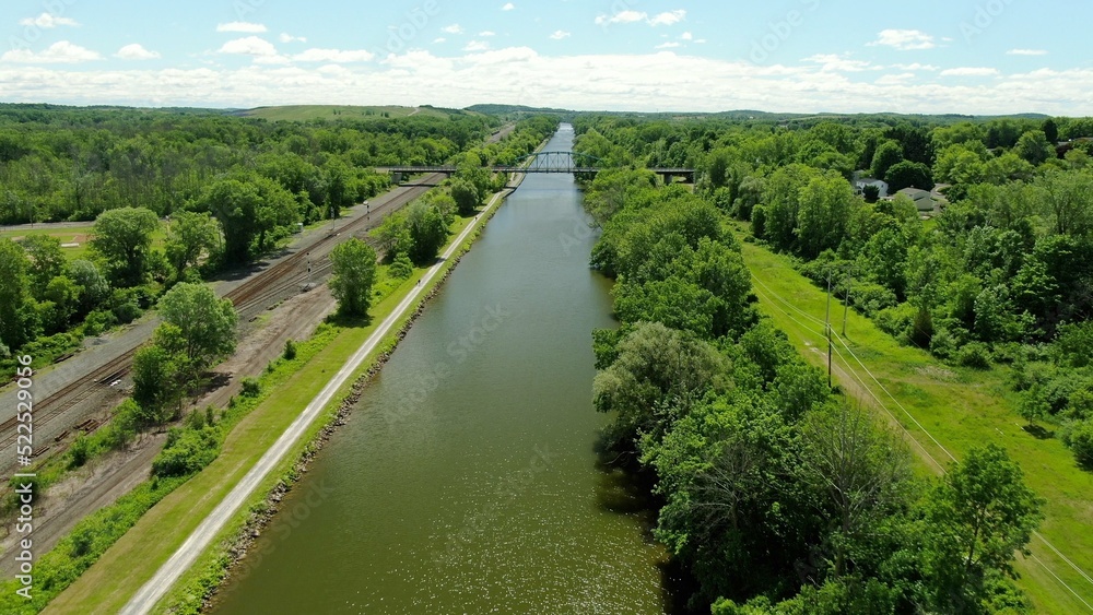 The Erie Canal flows through small american town in New York State during summertime surrounded by nature and hiking trail